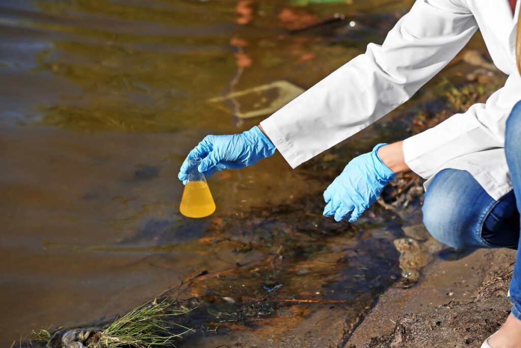 Toma de muestra de lodos con guantes y matraz en campo
