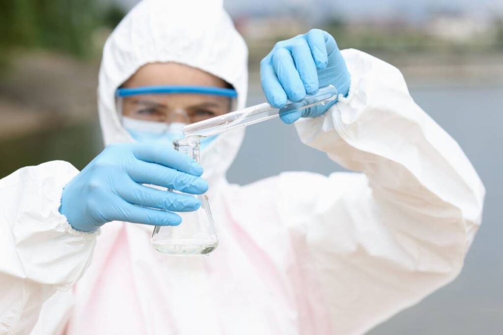 Analista con traje de protección y pipeta en laboratorio de análisis de aguas