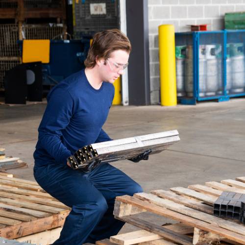 Trabajador cargando una pieza en un almacén: evaluación de riesgos ergonómicos